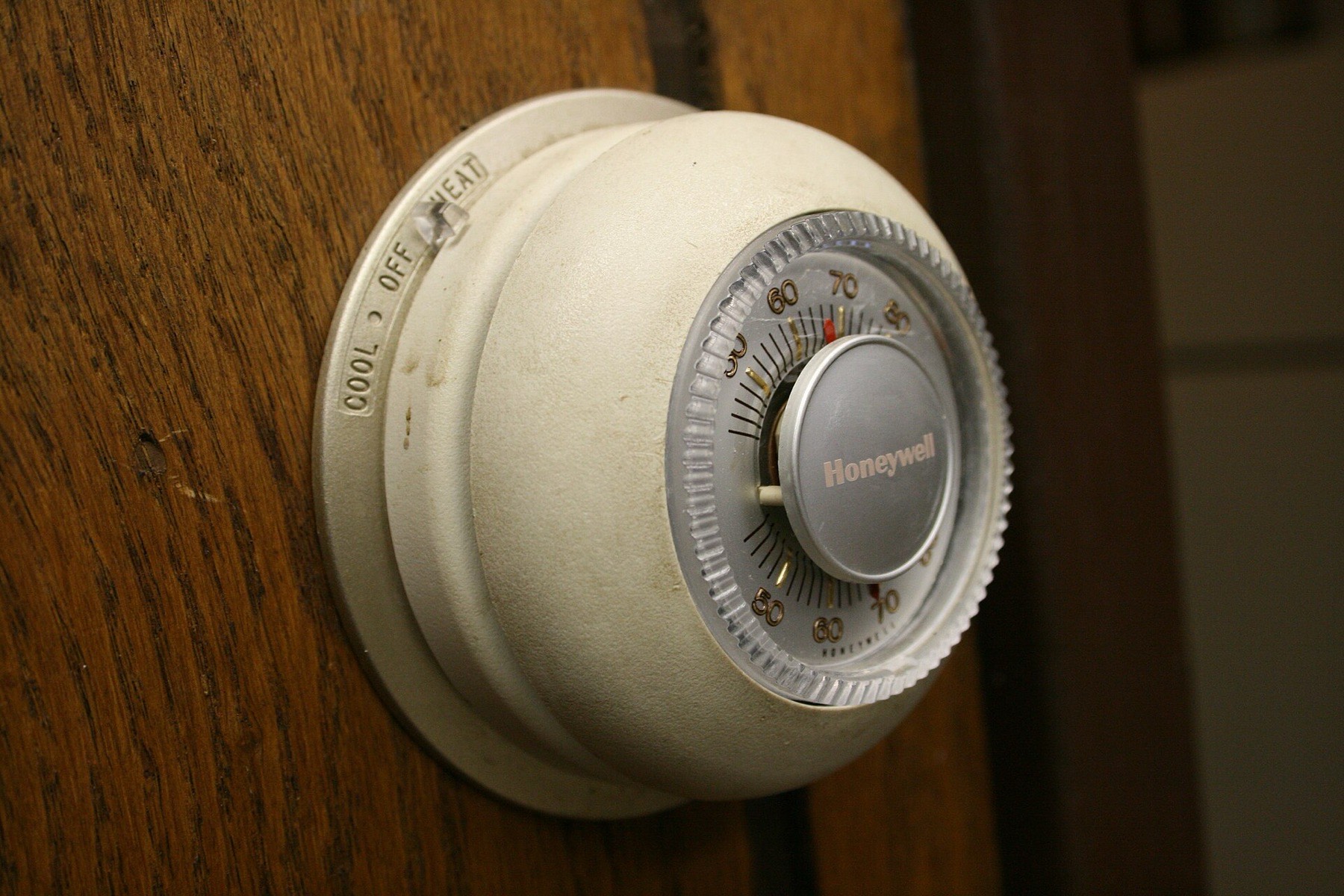 A classic round dial thermostat on a wood-panelled wall
