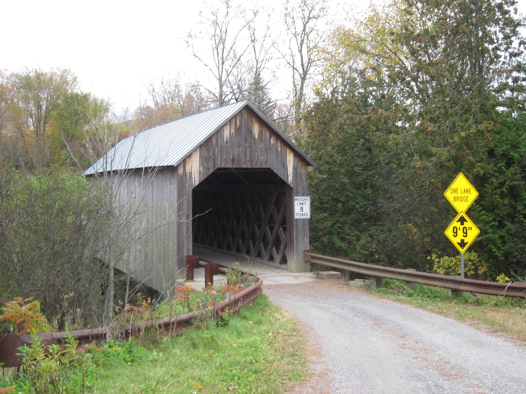 The wooden Halpin Covered Bridge on a gravel road in autumn