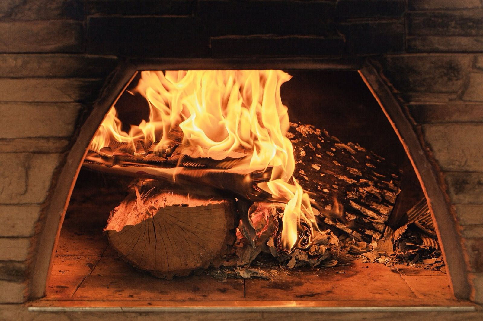 Logs burning in the mouth of a brick wood-fired oven