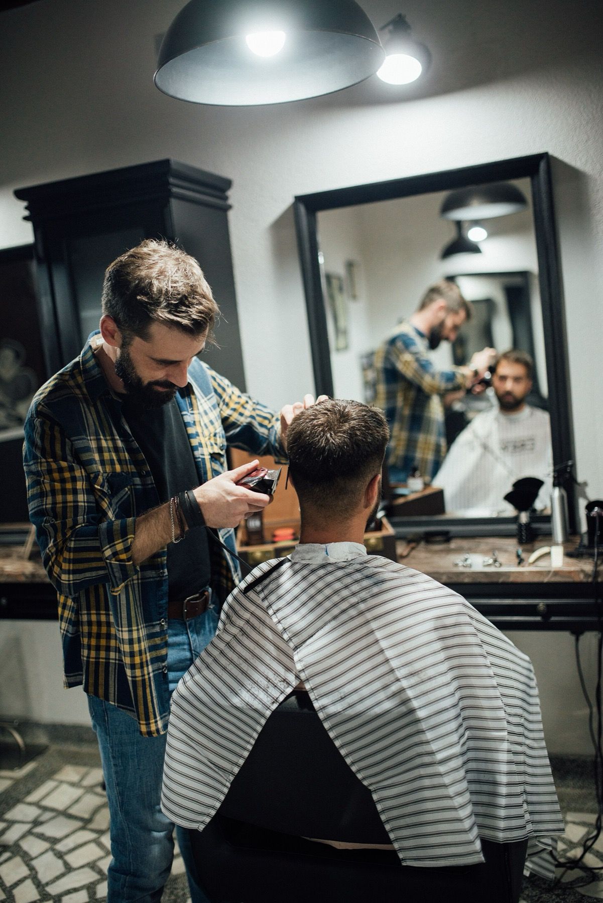 A barber cutting a client's hair in front of a mirror