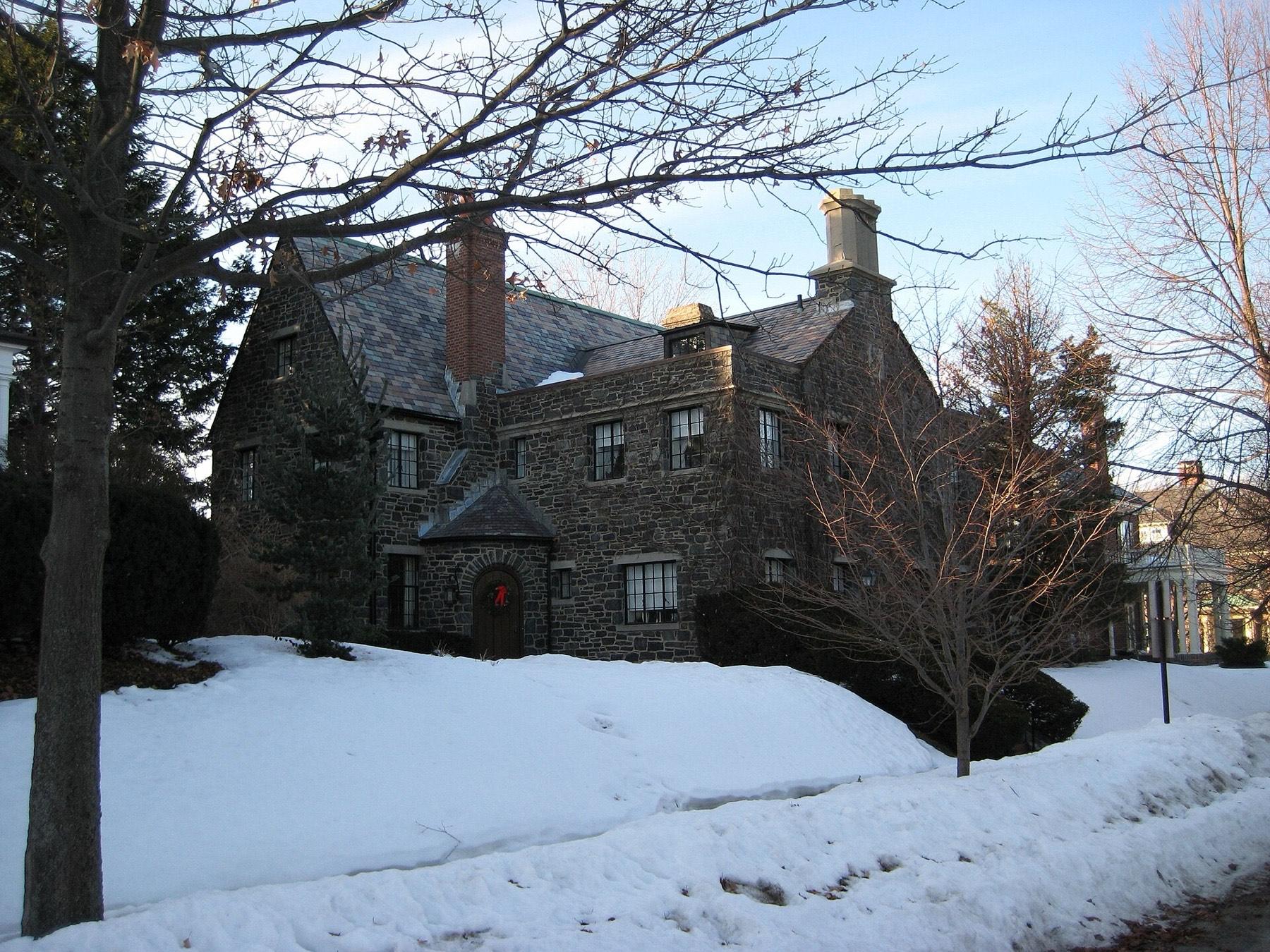 A stone house among bare trees in Portland's West End after snowfall