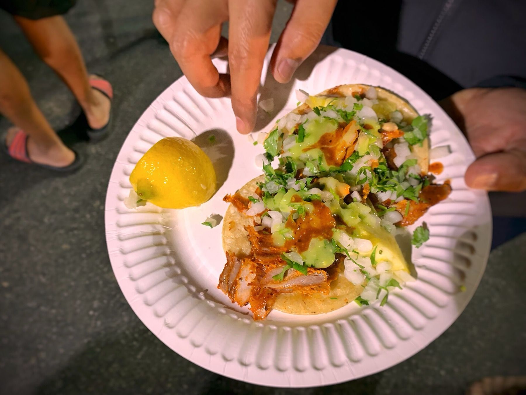 Tacos al pastor with lime on a paper plate